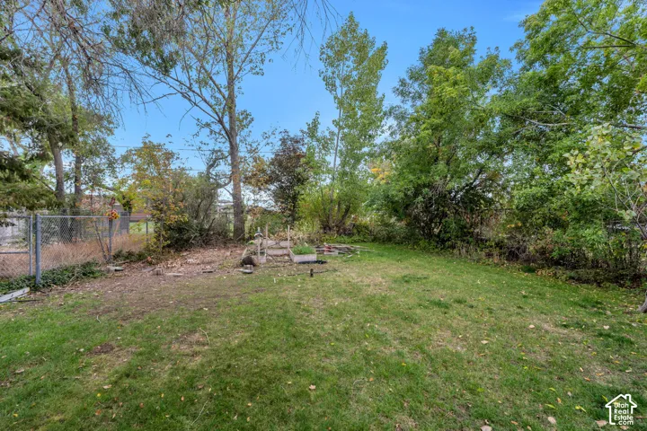 Expansive lawn area with mature trees and a chain-link fence