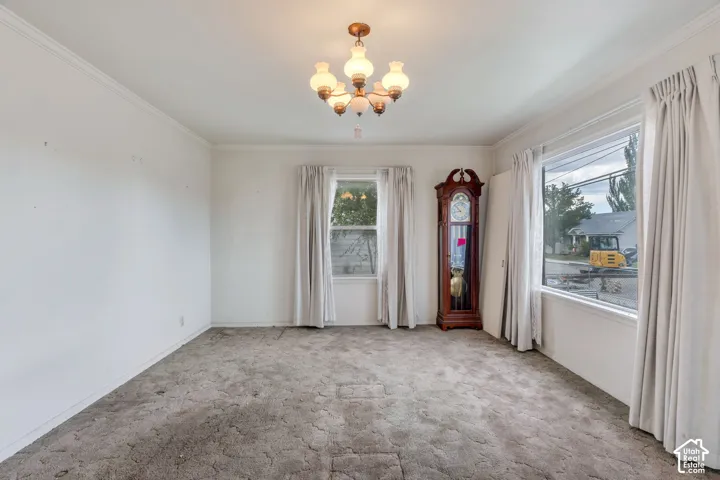 Crown molding detail, overhead chandelier, and multiple windows providing ample natural light
