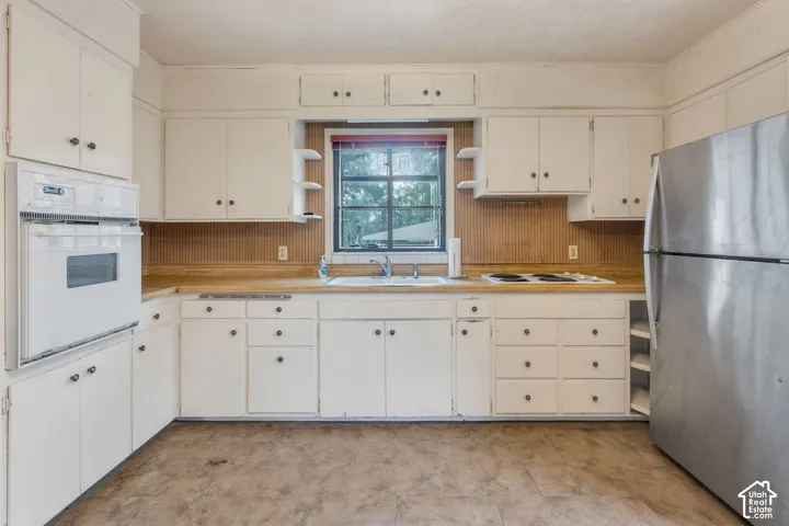 Kitchen featuring white cabinetry, wood-finish countertops, and built-in oven