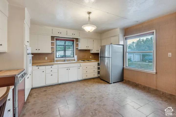 Galley-style kitchen featuring white cabinetry, an integrated wall oven, and a double-basin sink