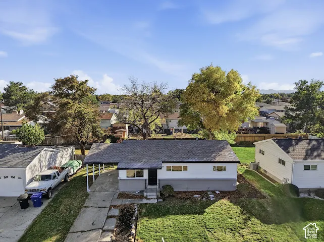 Single-story residence featuring a covered carport, concrete driveway, and expansive lawn area