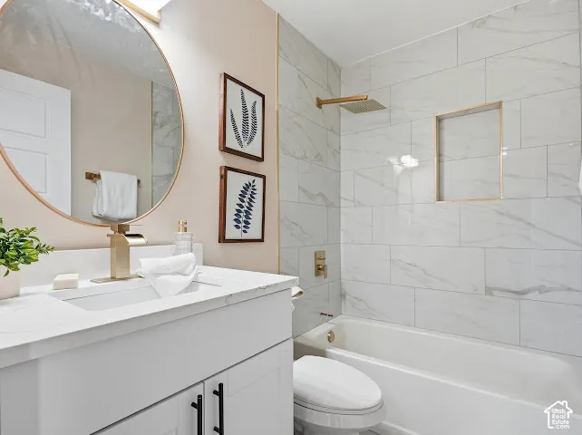 White shaker-style vanity with a stone-composite countertop, integrated rectangular sink, large-format tile surround in the shower, and gold-finish fixtures