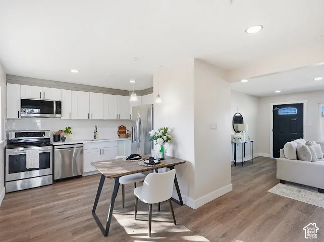 Kitchen featuring white cabinetry, stainless steel appliances, wood-finish flooring, and recessed lighting