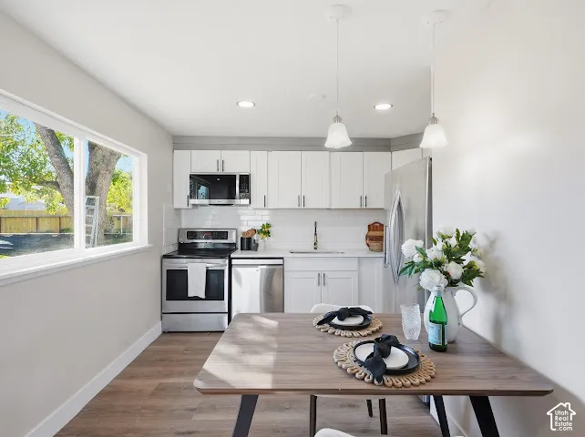 Kitchen featuring white shaker-style cabinetry, stainless steel appliances, subway tile backsplash, recessed lighting, and dual glass pendant fixtures