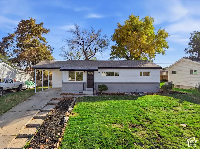 Single-story exterior featuring a dual-tone facade, attached carport, concrete driveway, and front lawn