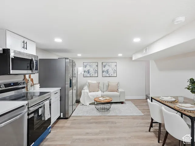 Kitchen featuring white shaker-style cabinetry, stainless steel appliances, recessed lighting, and wood-finish flooring