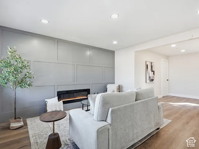 Interior space featuring a recessed electric fireplace set into a floor-to-ceiling grid-pattern accent wall, wood-finish flooring, and recessed LED ceiling lighting