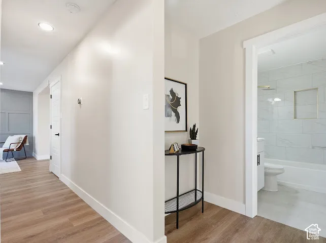 Interior hallway featuring wood-finish flooring, recessed lighting, and a bathroom with subway-tiled walls and a built-in recessed shower niche