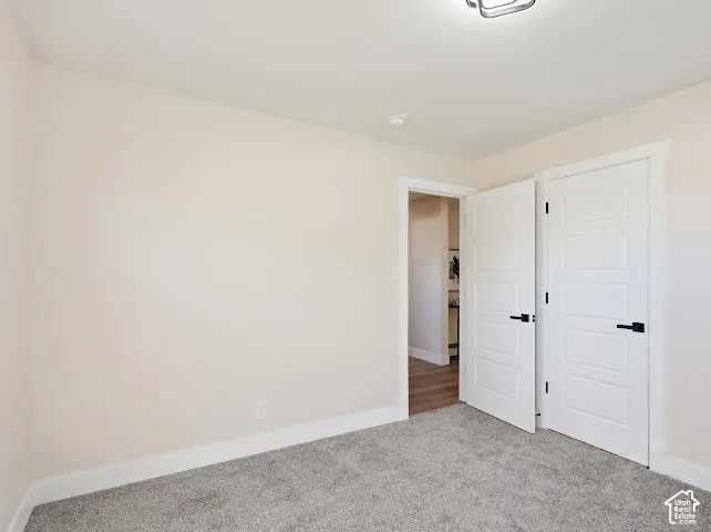 Neutral-toned interior room featuring gray carpeting, five-panel interior doors, and matte black hardware