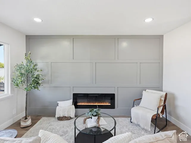Wall-to-wall grid-patterned wainscoting with a painted finish, recessed lighting, and a built-in linear electric fireplace