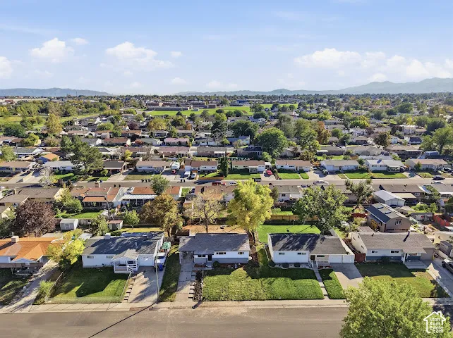 Aerial perspective featuring established residential lots with mature trees and mountain range backdrop