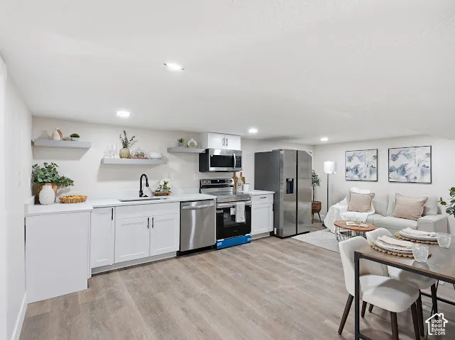 Kitchen featuring white cabinetry, wood-finish flooring, stainless steel appliances, solid-surface countertops, and recessed lighting