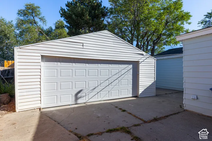 Detached garage with white panel siding and a paneled garage door