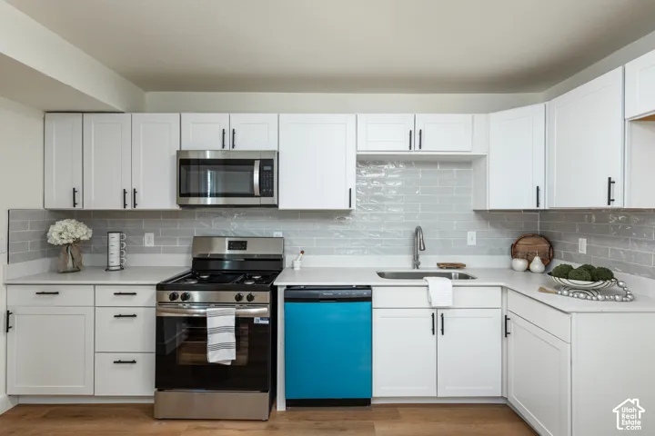 White shaker cabinetry, light-toned countertops, subway tile backsplash, and wood-finish flooring