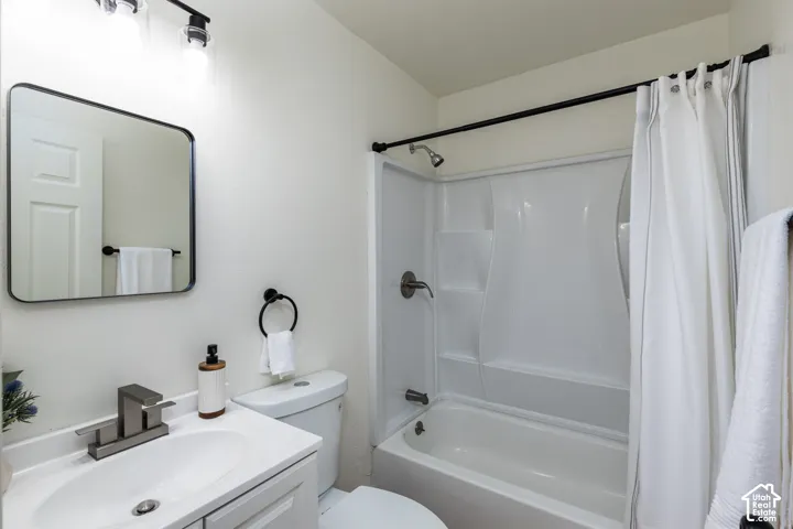 Bathroom featuring a single vanity, undermount sink, brushed nickel faucet, rounded rectangular mirror, and a white tub with integrated shower