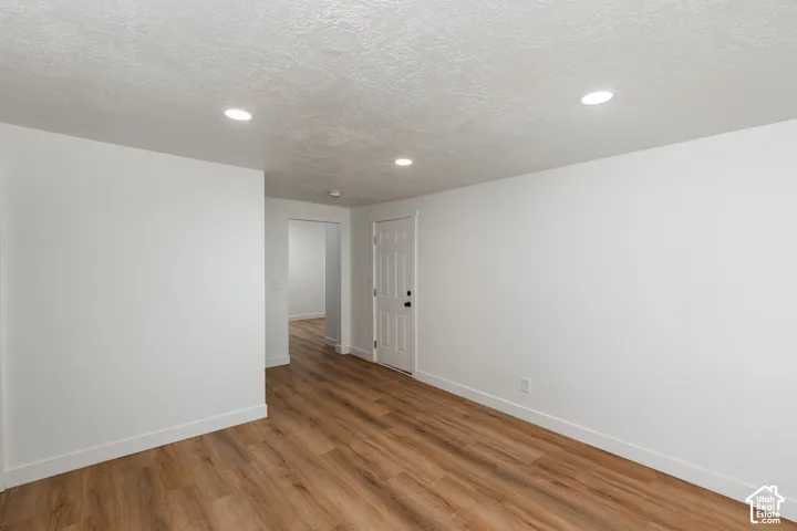 Recessed lighting, wood-finish flooring, white trim, and a paneled door