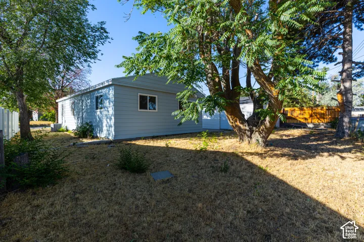 Rear exterior with light blue siding, multiple windows, and mature trees