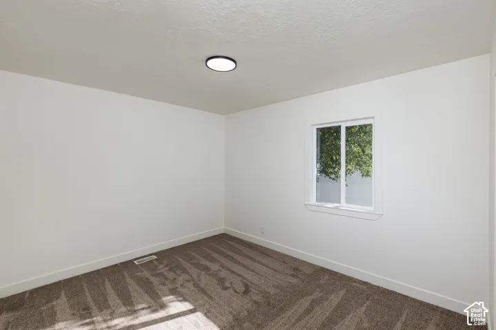 Neutral wall paint with textured ceiling finish, modern flush-mount ceiling light, and a white-framed window