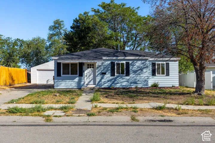 Light blue siding exterior with black shutters, white front door, and a detached garage featuring a white garage door