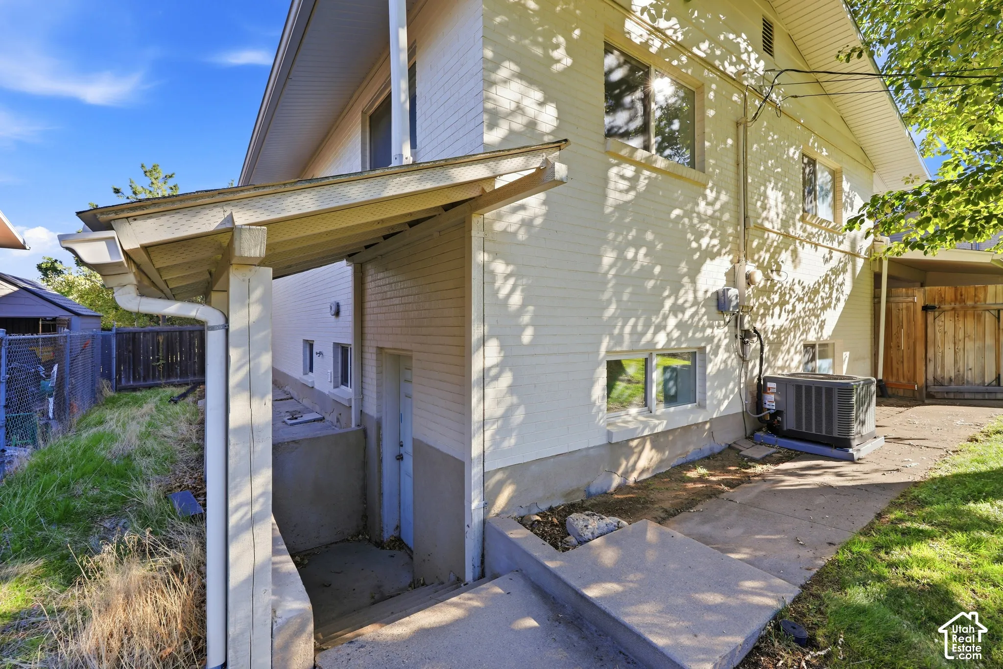 Exterior featuring white siding, multiple windows, a covered concrete patio, and an air conditioning unit