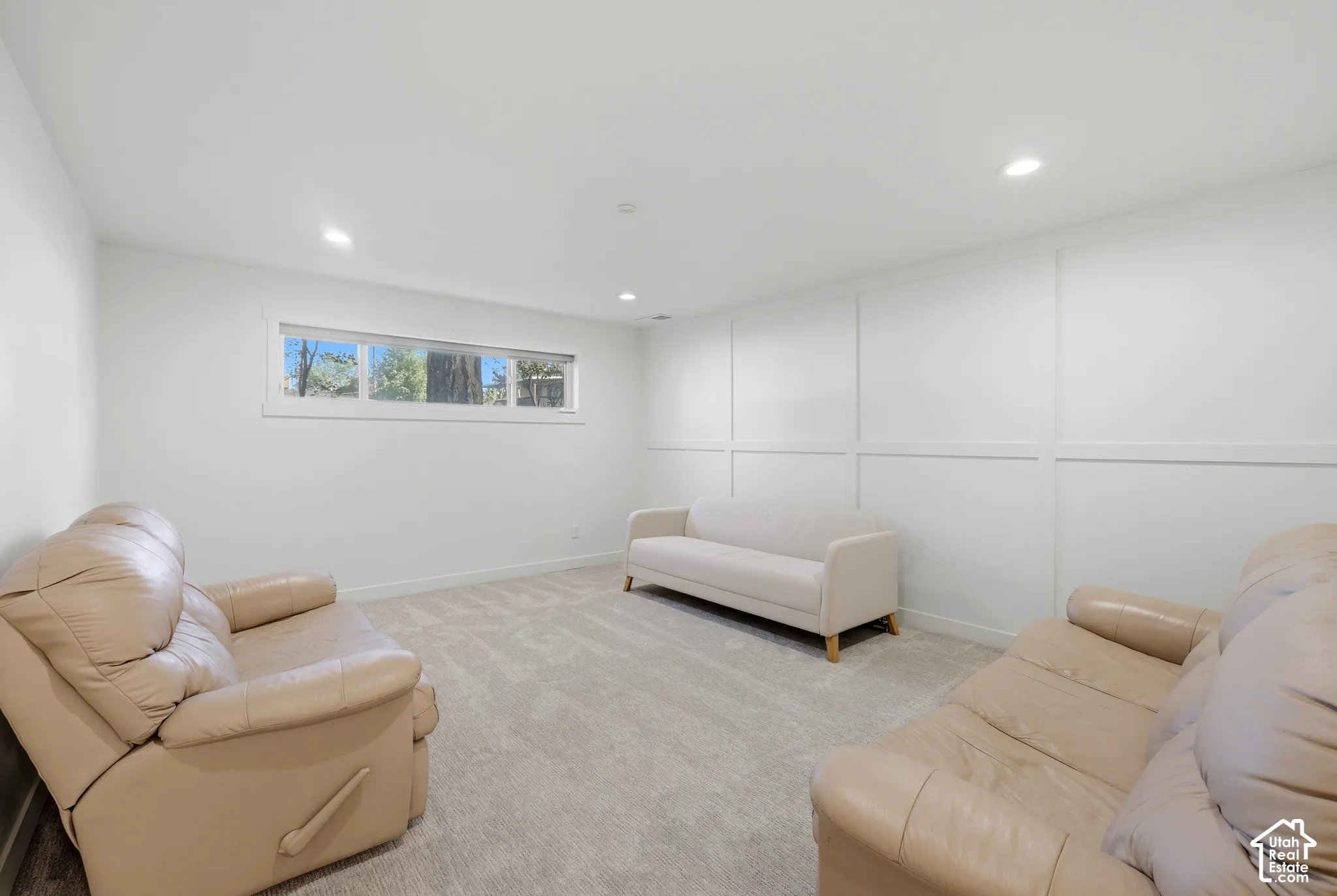 Recessed lighting, wall paneling, light-toned carpeting, and a window
