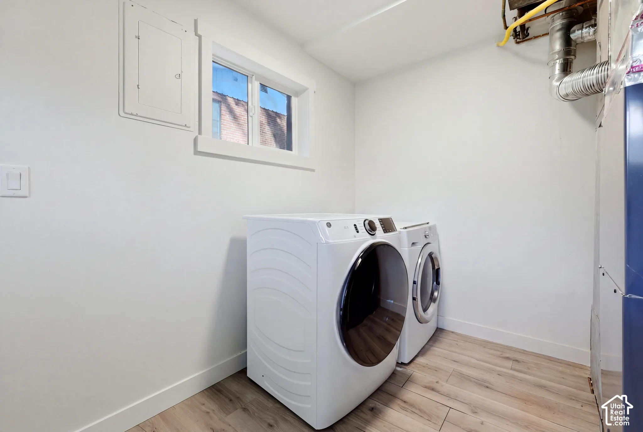 Wood-finish flooring with white baseboards, a window with white trim, and white painted walls