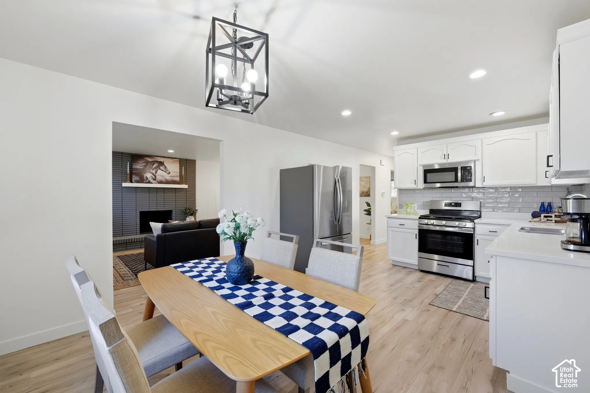 Open-concept dining area with wood-finish flooring, a modern geometric chandelier, and recessed lighting