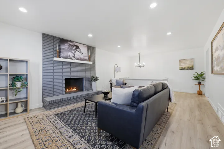 Recessed lighting, wood-finish flooring, and a fireplace with a gray brick surround and hearth