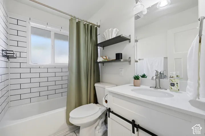 White subway tile shower surround, window with frosted pane, white vanity with integrated sink, brushed nickel faucet, and barn door style cabinetry