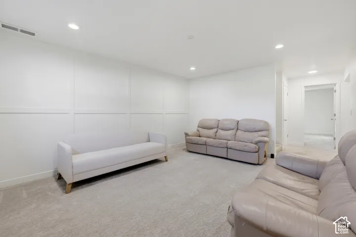 Recessed lighting, wall paneling, light-toned carpet flooring, white walls, and a white ceiling create a bright interior
