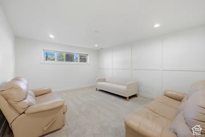 Recessed lighting, wall paneling, light-toned carpeting, and a window