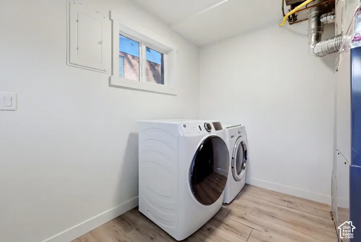 Wood-finish flooring with white baseboards, a window with white trim, and white painted walls