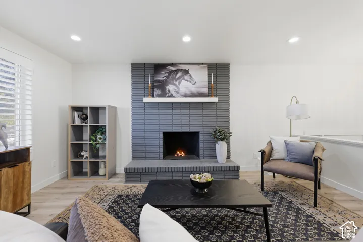 Recessed lighting illuminates the living space featuring wood-finish flooring and a fireplace with a mantel
