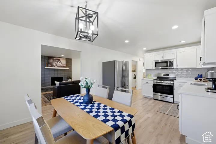 Open-concept dining area with wood-finish flooring, a modern geometric chandelier, and recessed lighting