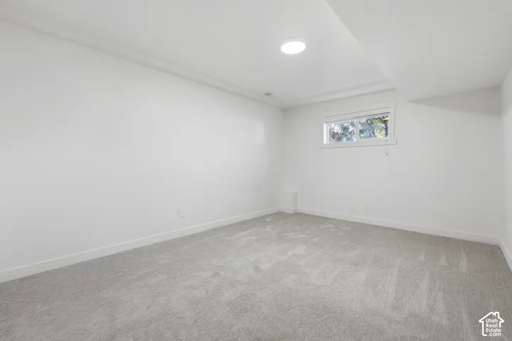 Recessed lighting, light gray carpeting, and a single window with white trim
