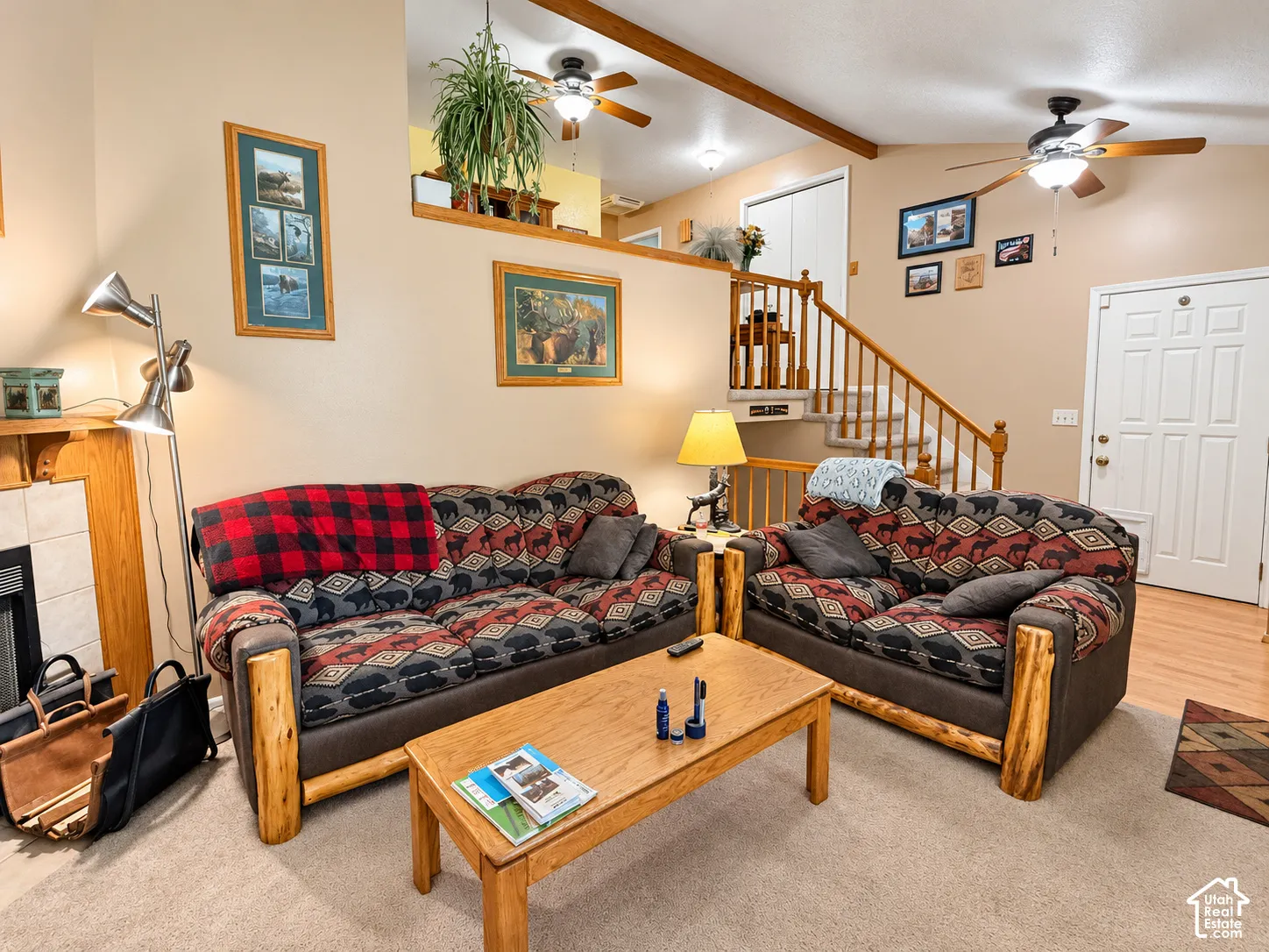Spacious living area featuring exposed wood beam ceiling, wood-finish flooring throughout, and abundant natural lighting from multiple windows