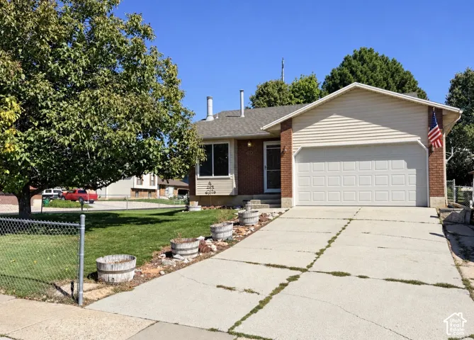 Brick facade, attached garage, sloped roof, front lawn, mature tree