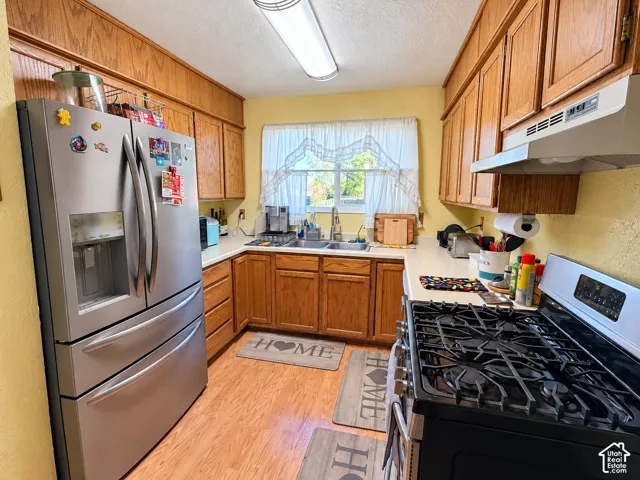 U-shaped kitchen featuring wood-finish cabinetry, solid surface countertops, and wood-finish flooring