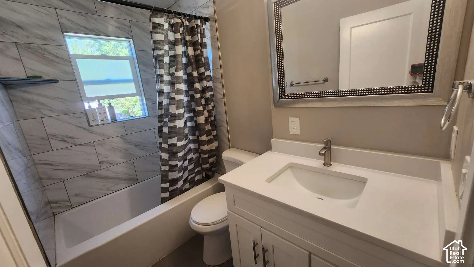 Bathroom featuring a white vanity with an integrated sink, brushed nickel faucet, and a framed mirror
