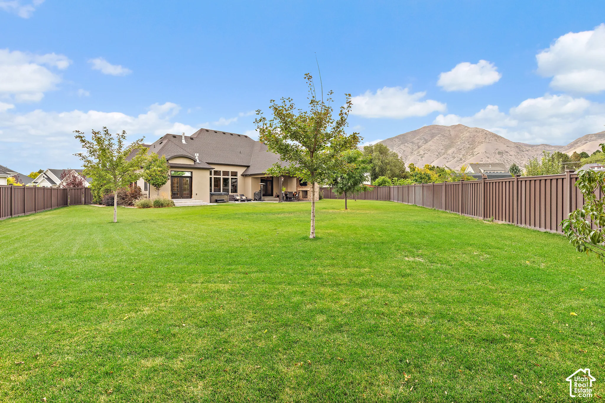 Expansive lawn with perimeter fencing, mature trees, and mountain scenery