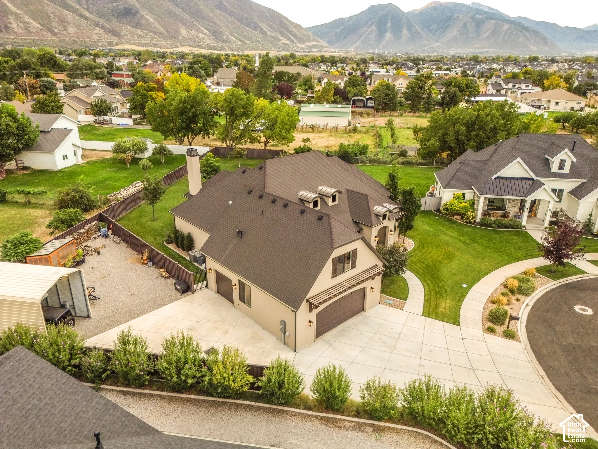 Mountain backdrop, large lot, paved driveway, attached garage, and mature landscaping