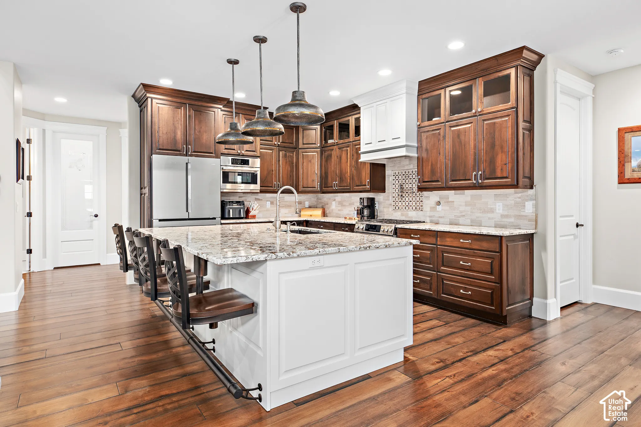Gourmet kitchen with wood-finish flooring, a spacious island featuring a stone countertop, and stainless steel appliances