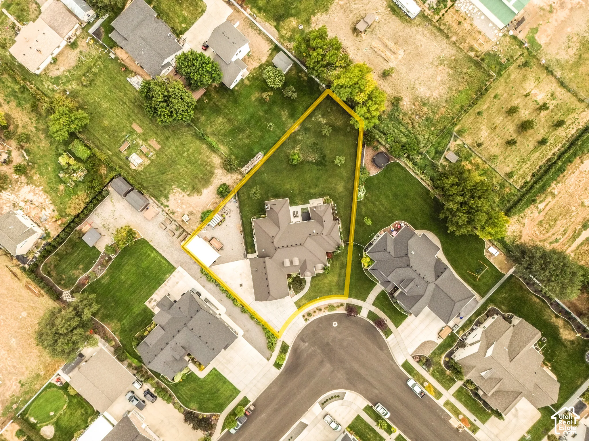 Aerial view highlighting a cul-de-sac street, surrounding residences, and a substantial lot with mature trees