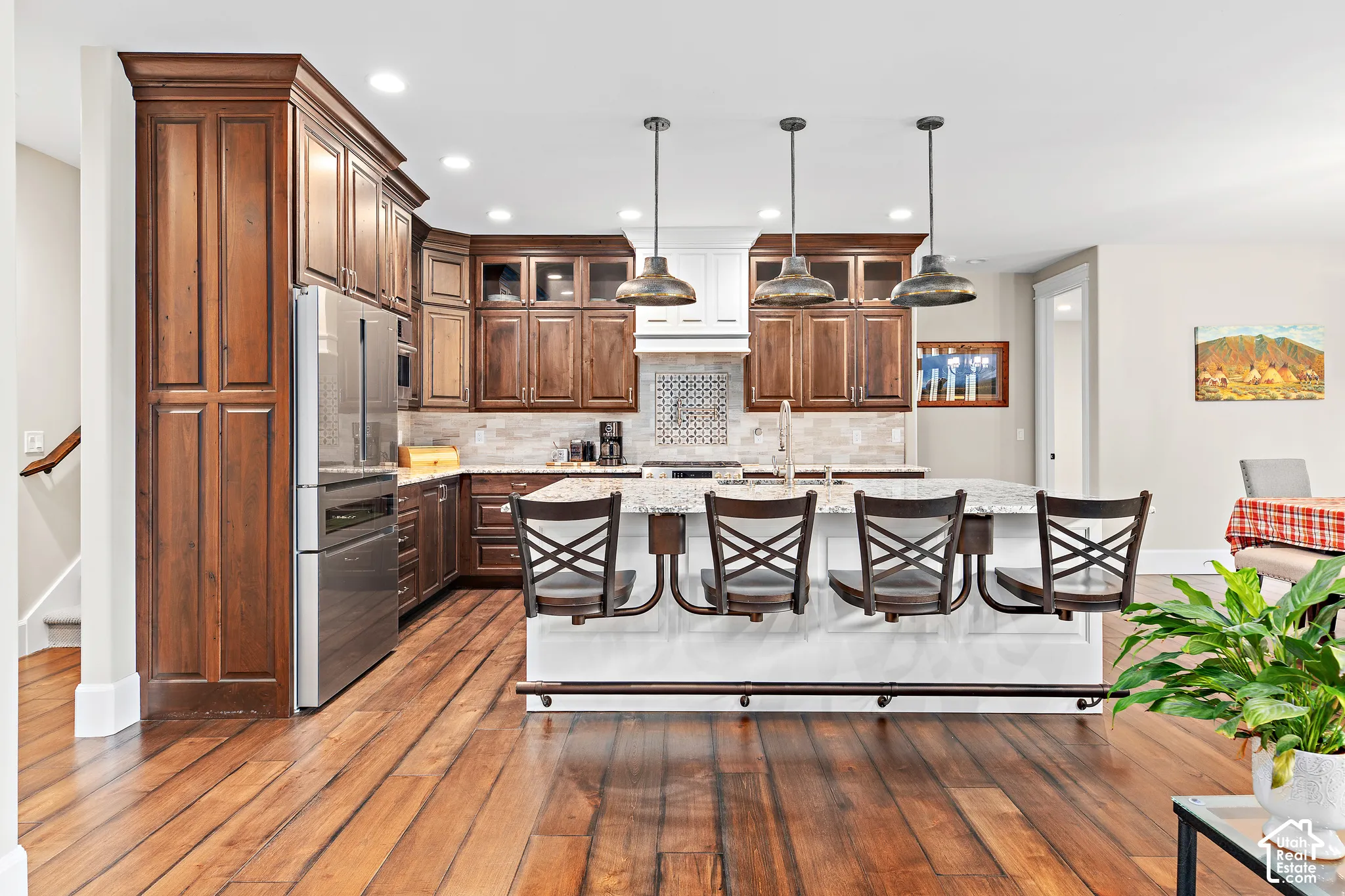 Gourmet kitchen with wood-finish flooring, stainless steel appliances, and a central island featuring a stone countertop