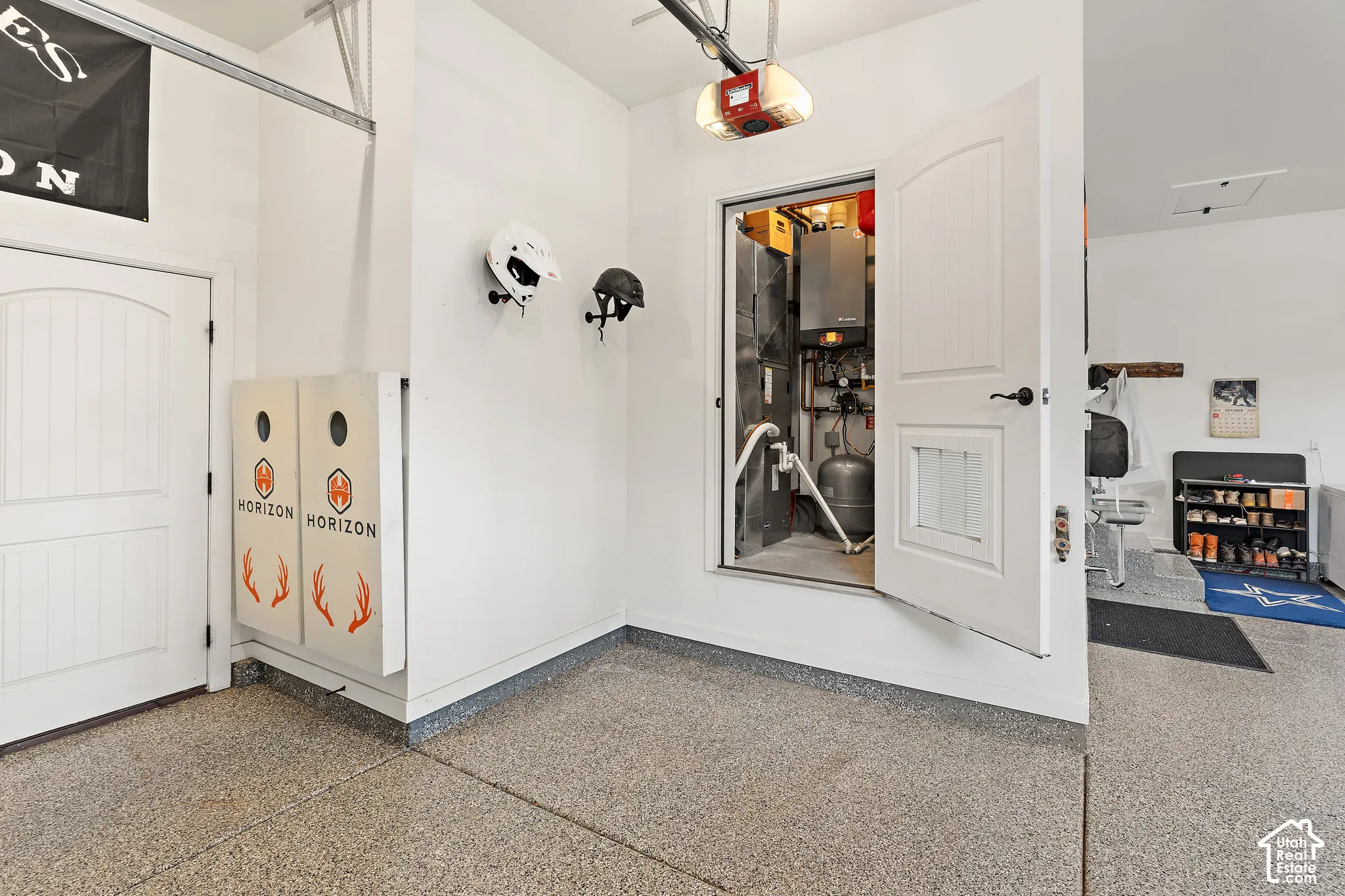 Garage with speckled epoxy flooring, white paneled doors, and a utility closet