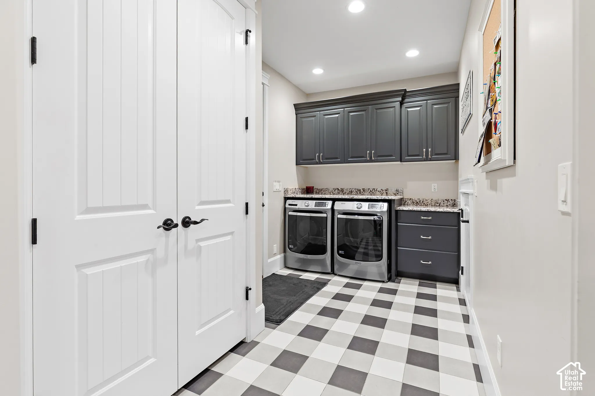 Checkered tile flooring with gray and white squares, dark gray cabinetry, stone-finish countertops, and recessed lighting