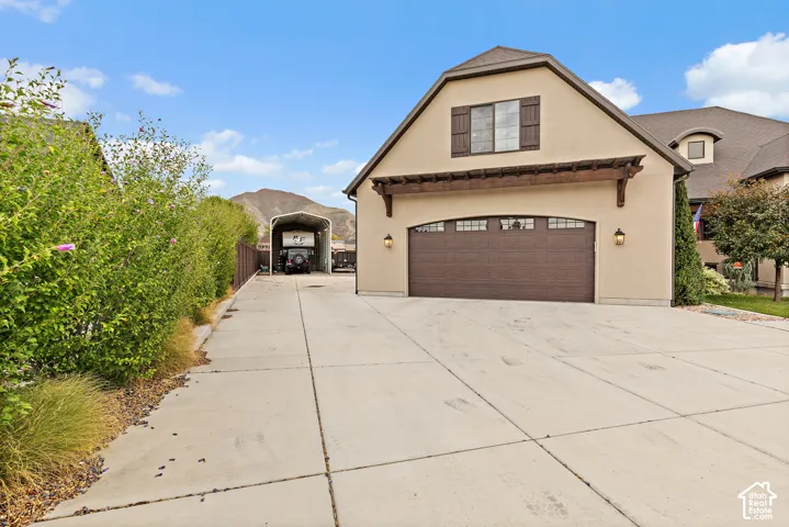 Two-car garage with a wood-finish door, sconce lighting, and decorative window shutters