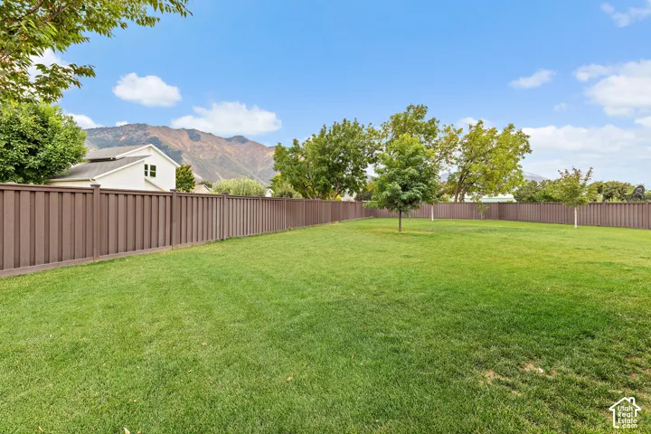 Expansive lawn area with a perimeter privacy fence and established trees