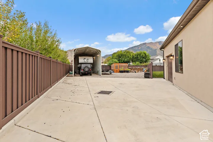 Extended concrete driveway leading to a metal carport structure and a stucco exterior