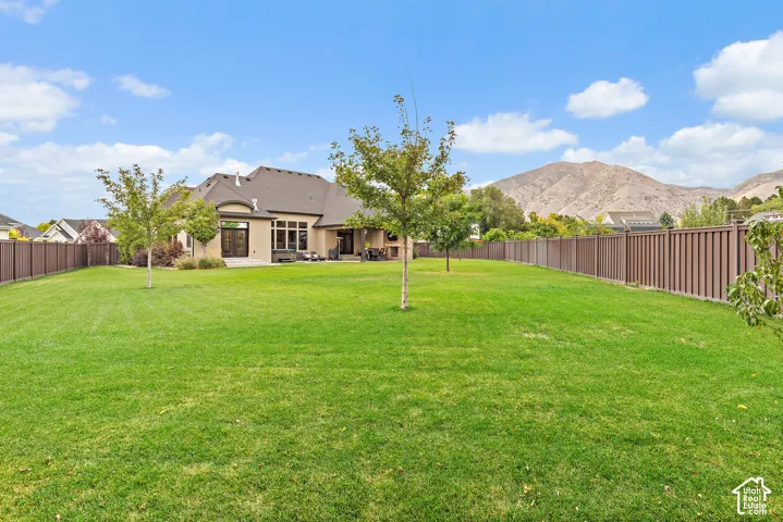 Expansive lawn with perimeter fencing, mature trees, and mountain scenery